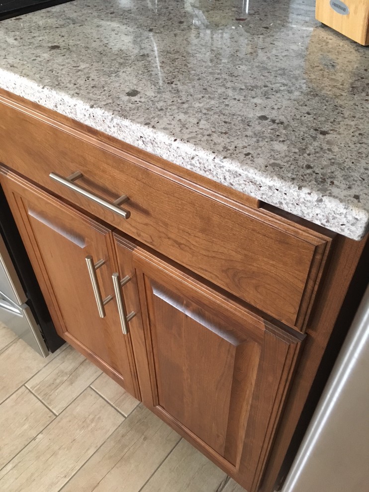 Example of a small transitional single-wall enclosed kitchen design with raised-panel cabinets, medium tone wood cabinets, quartzite countertops, multicolored backsplash, matchstick tile backsplash and stainless steel appliances