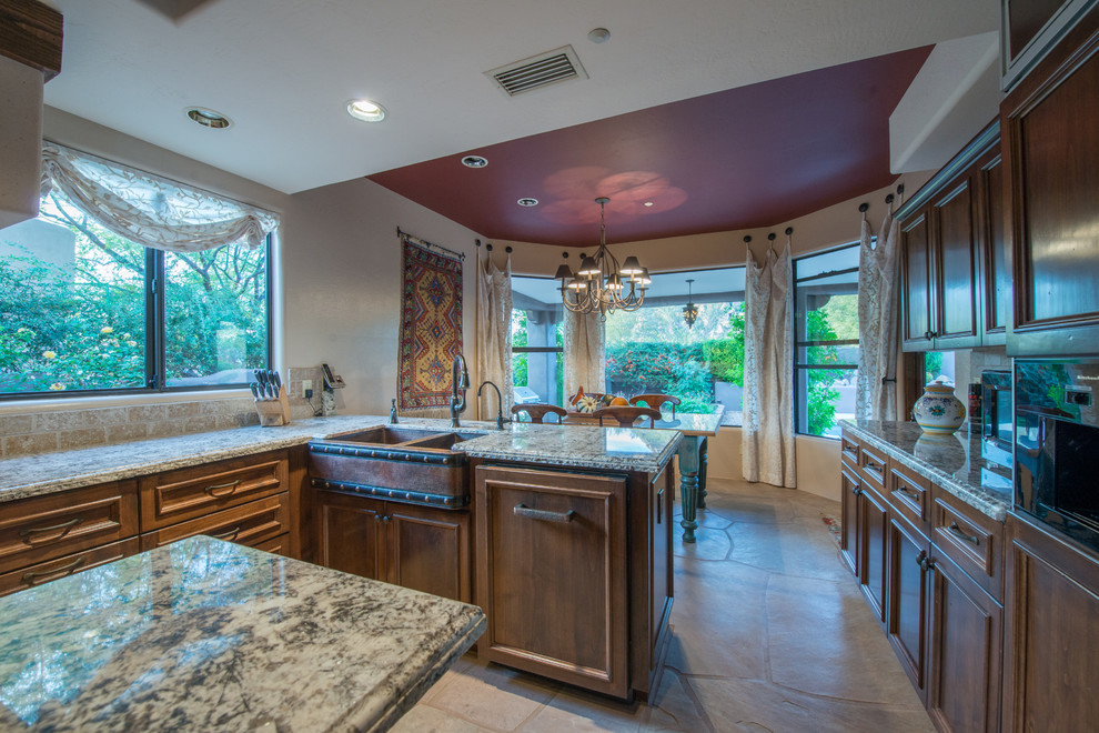 Large mountain style slate floor eat-in kitchen photo in Phoenix with a farmhouse sink, raised-panel cabinets, dark wood cabinets, granite countertops, beige backsplash, stone tile backsplash, paneled appliances and an island