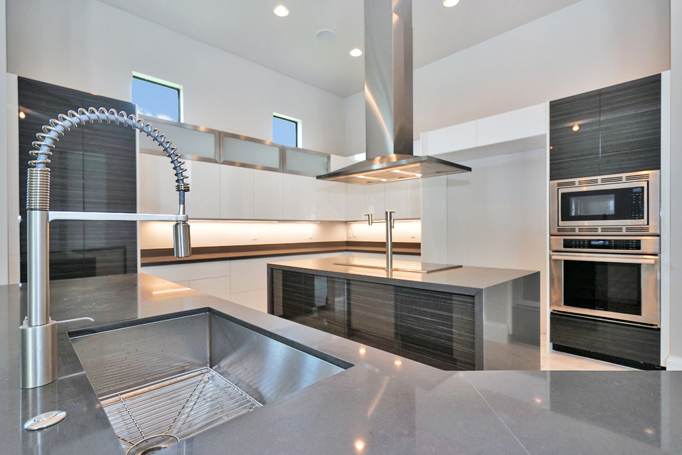 Photo of a large contemporary l-shaped open plan kitchen in Miami with an undermount sink, flat-panel cabinets, white cabinets, concrete benchtops, beige splashback, stainless steel appliances, marble floors, multiple islands and white floor.