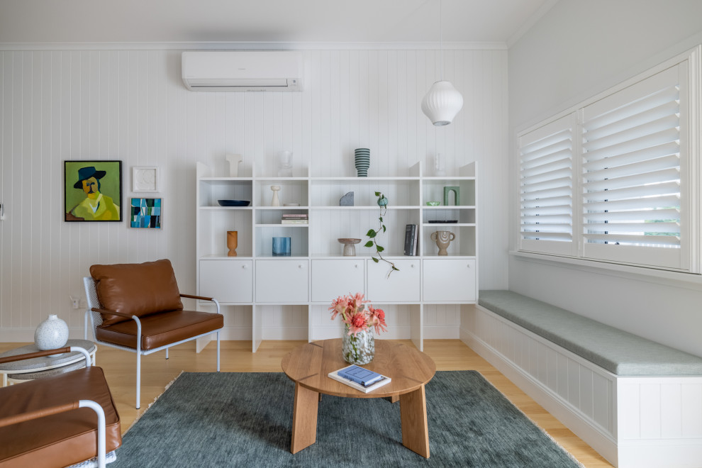 Design ideas for a mid-sized beach style open concept living room in Townsville with a library, white walls, light hardwood floors and wood walls.