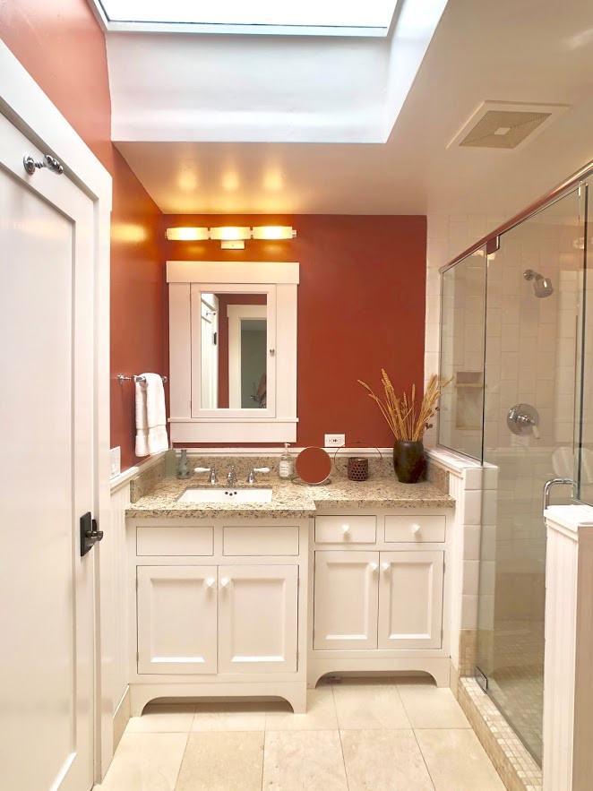 Exemple d'une petite salle d'eau chic avec un placard en trompe-l'oeil, des portes de placard blanches, une douche d'angle, un carrelage blanc, des carreaux de céramique, un mur orange, un sol en calcaire, un lavabo encastré, un plan de toilette en granite, un sol beige, une cabine de douche à porte battante, un plan de toilette beige, meuble simple vasque et meuble-lavabo encastré.