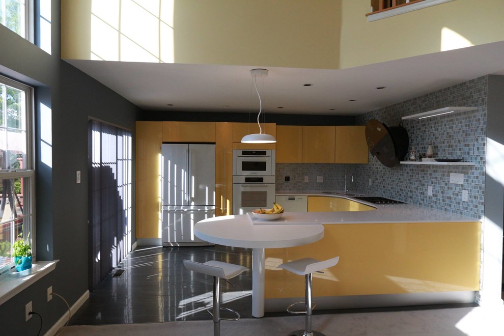 This is an example of a large contemporary u-shaped kitchen in Philadelphia with an undermount sink, glass tile splashback, white appliances, grey floor, flat-panel cabinets, yellow cabinets, solid surface benchtops, grey splashback and no island.
