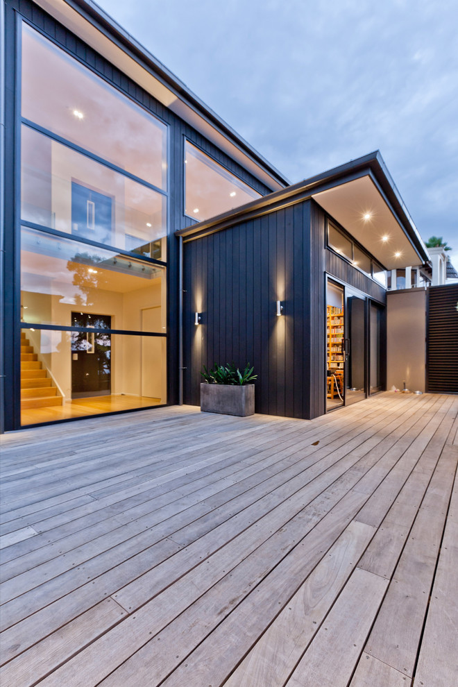 This is an example of a large contemporary side yard deck in Auckland with an outdoor kitchen and a pergola.