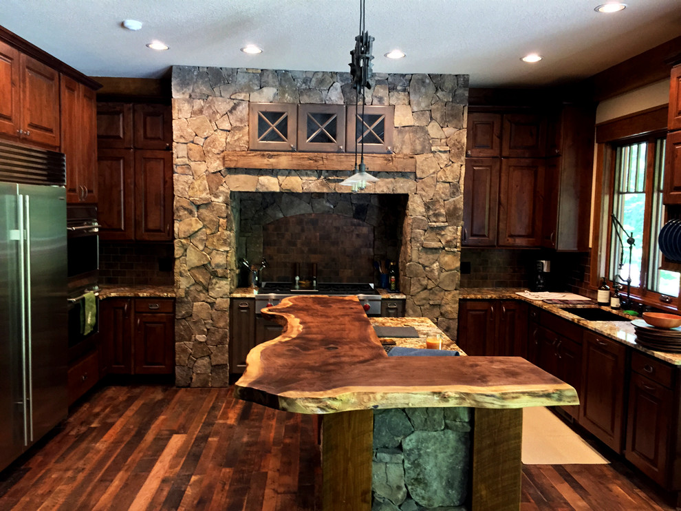 Design ideas for a mid-sized country u-shaped open plan kitchen in Nashville with an undermount sink, raised-panel cabinets, medium wood cabinets, wood benchtops, brown splashback, stone tile splashback, stainless steel appliances, medium hardwood floors and with island.