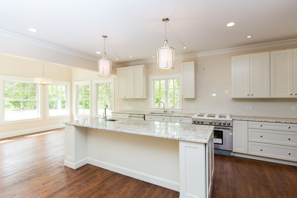 This is an example of a large transitional l-shaped open plan kitchen in Boston with recessed-panel cabinets, white cabinets, stainless steel appliances, medium hardwood floors and with island.