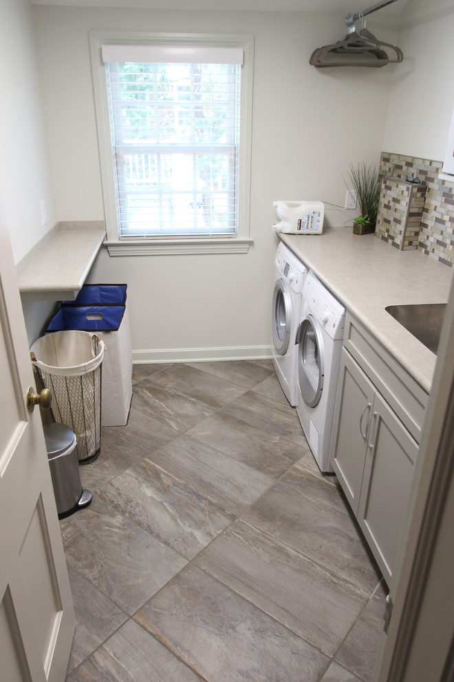 Small transitional galley dedicated laundry room in Cleveland with a single-bowl sink, shaker cabinets, grey cabinets, laminate benchtops, grey walls, porcelain floors and a side-by-side washer and dryer.