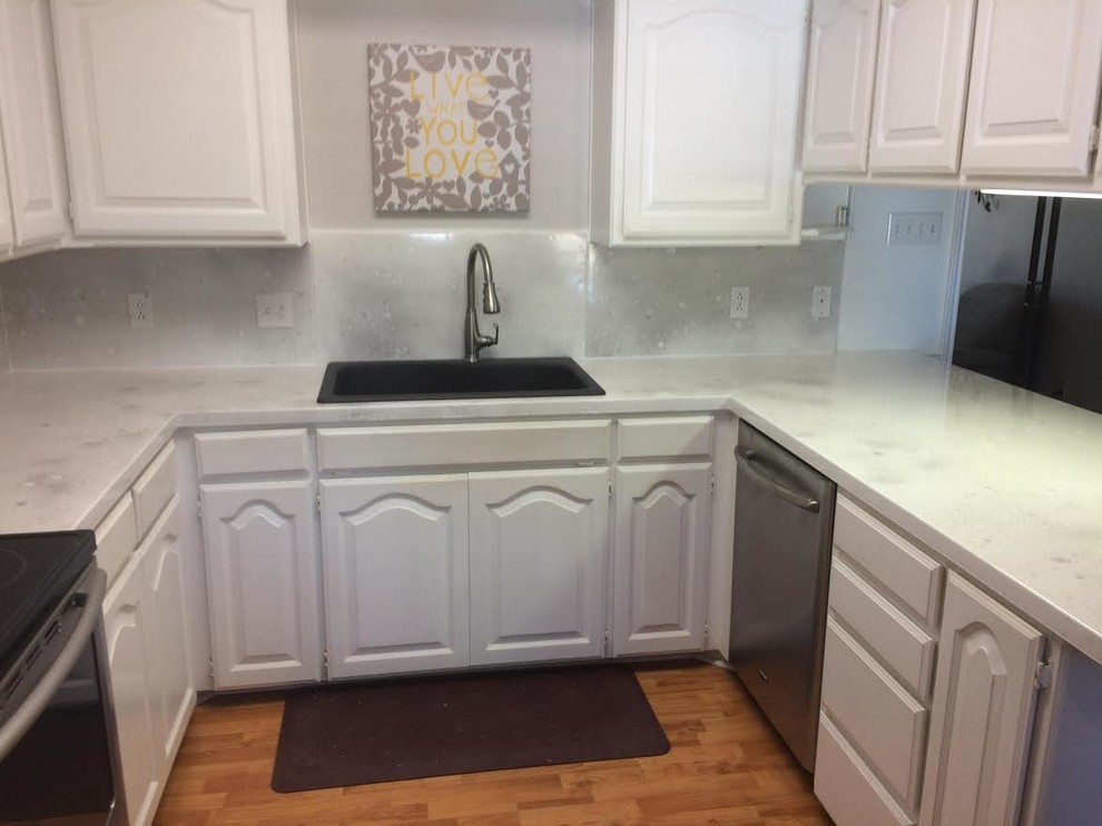 Mid-sized transitional u-shaped dark wood floor and brown floor enclosed kitchen photo in Austin with a drop-in sink, raised-panel cabinets, white cabinets, quartz countertops, white backsplash, stone slab backsplash, stainless steel appliances and a peninsula