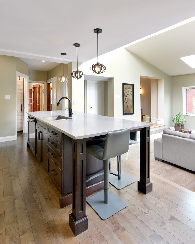 Inspiration for a transitional single-wall medium tone wood floor and brown floor open concept kitchen remodel in Ottawa with a double-bowl sink, shaker cabinets, white cabinets, white backsplash, subway tile backsplash, black appliances and an island