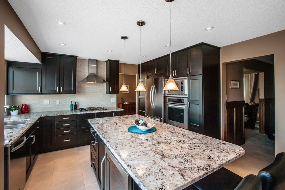 Enclosed kitchen - mid-sized transitional u-shaped ceramic tile and beige floor enclosed kitchen idea in Calgary with a double-bowl sink, shaker cabinets, dark wood cabinets, granite countertops, beige backsplash, matchstick tile backsplash, stainless steel appliances and an island