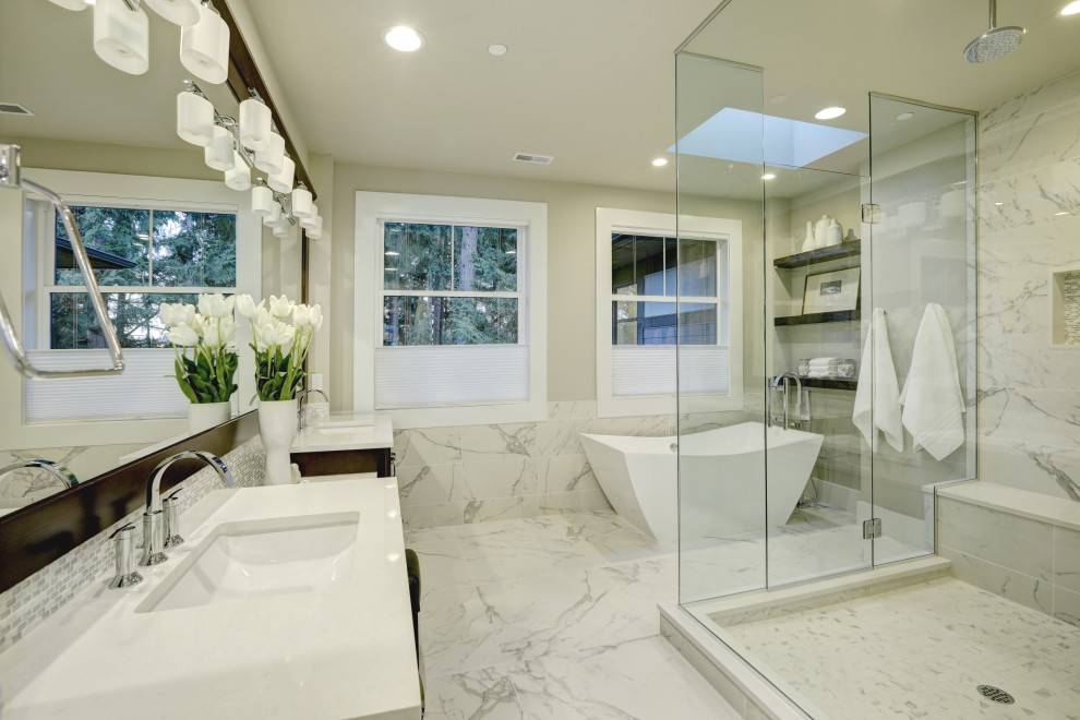 This is an example of a mid-sized arts and crafts master bathroom in Los Angeles with flat-panel cabinets, brown cabinets, a freestanding tub, a corner shower, white tile, marble, beige walls, marble floors, an undermount sink, white floor, a hinged shower door, white benchtops, a shower seat, a double vanity and a built-in vanity.