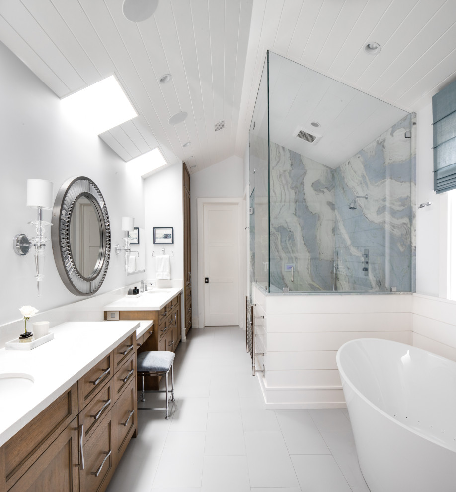 Beach style bathroom in Orange County with medium wood cabinets, a freestanding tub, a corner shower, multi-coloured tile, stone slab, white walls, an undermount sink, white floor, white benchtops and recessed-panel cabinets.