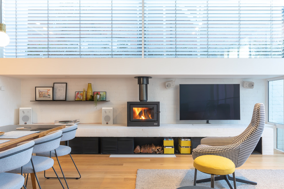 Inspiration for a mid-sized contemporary open concept living room in Melbourne with a wood stove, a brick fireplace surround, a freestanding tv and brown floor.