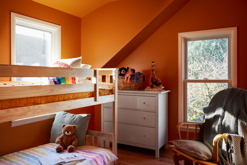 Aménagement d'une chambre d'enfant classique avec un mur orange et un sol en bois brun.