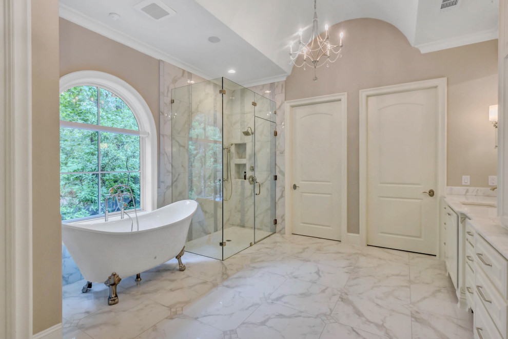 Photo of a large master bathroom in Houston with raised-panel cabinets, white cabinets, a claw-foot tub, a corner shower, beige walls, an undermount sink, brown floor, a hinged shower door, white benchtops, a niche, a double vanity, a built-in vanity and vaulted.