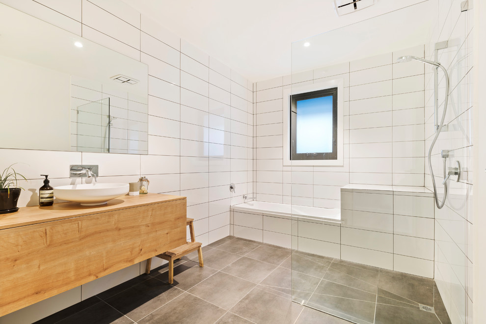 Contemporary wet room bathroom in Melbourne with flat-panel cabinets, medium wood cabinets, an alcove tub, white tile, a vessel sink, wood benchtops, grey floor, an open shower and brown benchtops.