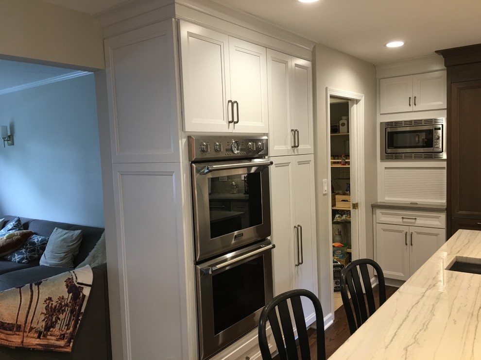 Inspiration for a large transitional u-shaped dark wood floor and brown floor open concept kitchen remodel in Chicago with an undermount sink, flat-panel cabinets, white cabinets, quartz countertops, gray backsplash, ceramic backsplash, stainless steel appliances, an island and gray countertops