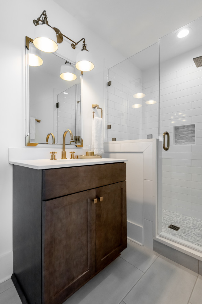 Mid-sized tropical bathroom in Charleston with shaker cabinets, dark wood cabinets, an alcove shower, a two-piece toilet, green tile, marble, white walls, porcelain floors, an integrated sink, engineered quartz benchtops, grey floor, a hinged shower door and white benchtops.