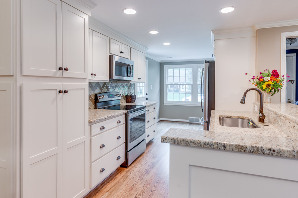 Design ideas for a small transitional galley eat-in kitchen in Kansas City with an undermount sink, shaker cabinets, white cabinets, granite benchtops, beige splashback, stone tile splashback, stainless steel appliances, light hardwood floors, a peninsula and brown floor.