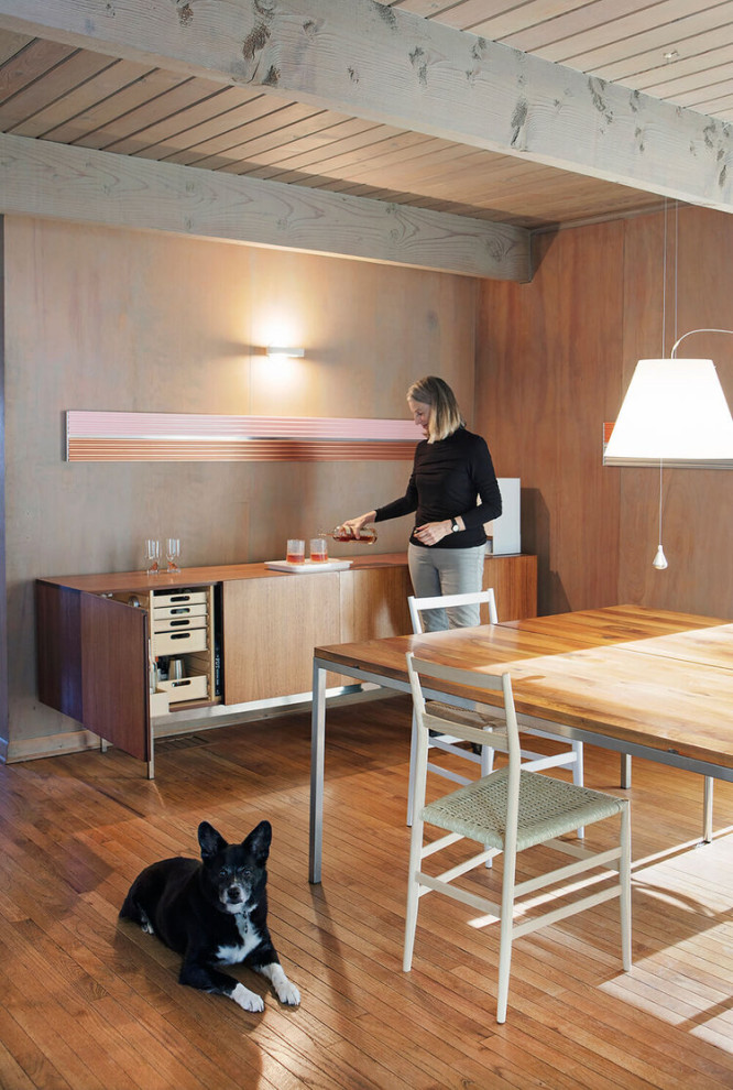 Foto di una piccola sala da pranzo moderna con pareti marroni, pavimento in legno massello medio, pavimento marrone, travi a vista e pareti in legno
