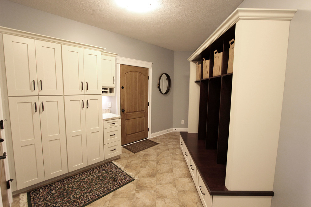 Photo of a mid-sized transitional mudroom in Cleveland with grey walls, ceramic floors, a single front door, a medium wood front door and beige floor.