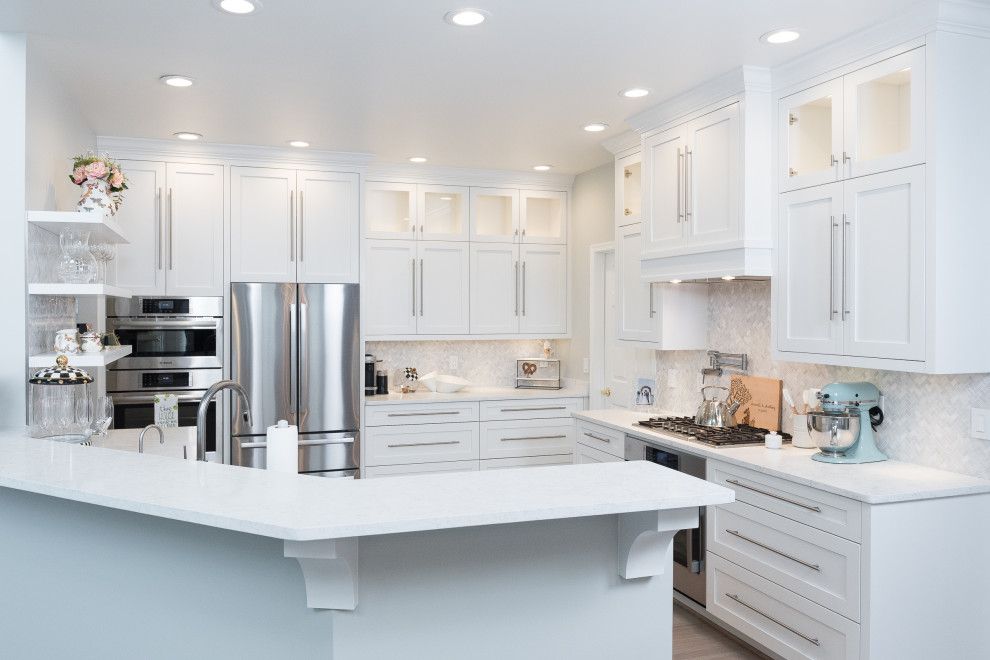 Inspiration for a transitional u-shaped kitchen in Detroit with shaker cabinets, white cabinets, grey splashback, stainless steel appliances, medium hardwood floors, a peninsula, brown floor and white benchtop.