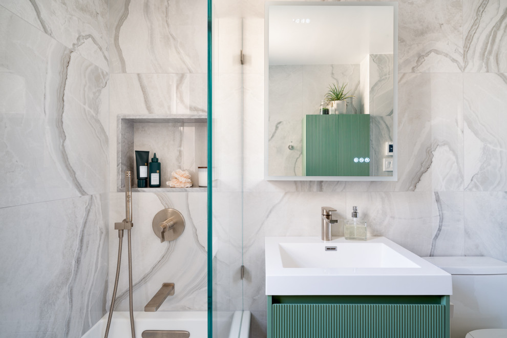 Стильный дизайн: главная ванная комната среднего размера в стиле модернизм с фасадами островного типа, зелеными фасадами, ванной в нише, душем над ванной, унитазом-моноблоком, белой плиткой, керамогранитной плиткой, белыми стенами, полом из керамогранита, врезной раковиной, столешницей из искусственного кварца, белым полом, душем с раздвижными дверями, белой столешницей, нишей, тумбой под одну раковину и подвесной тумбой - последний тренд