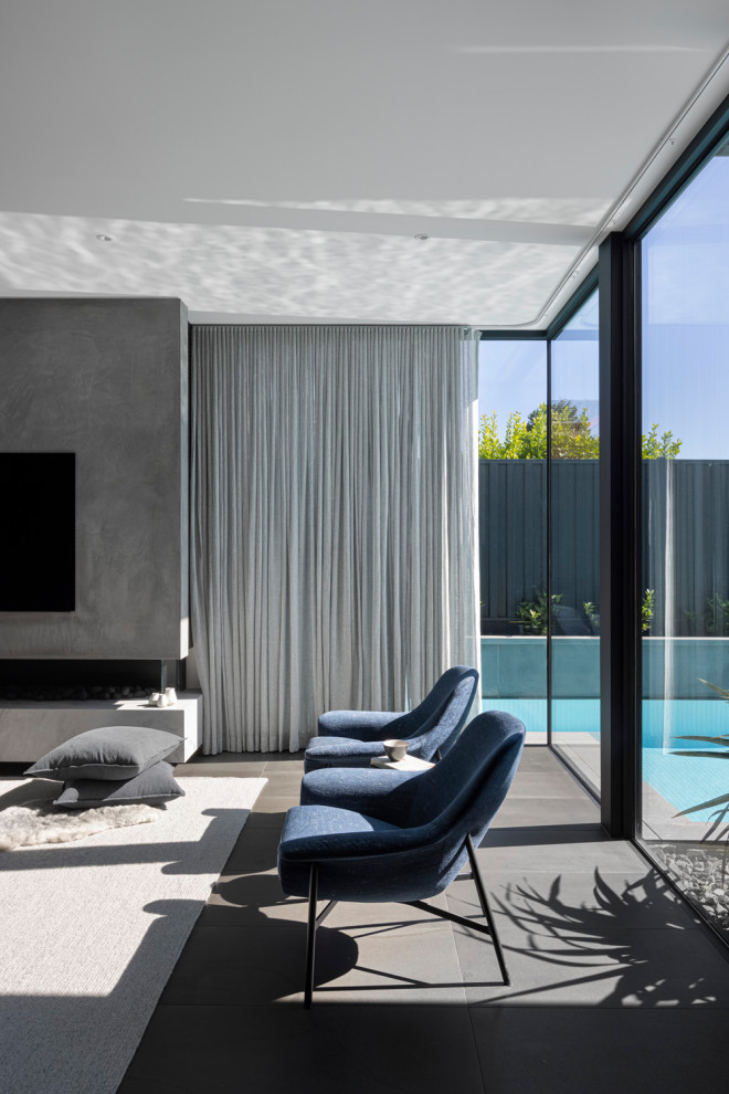 На фото: большая парадная, открытая гостиная комната в стиле модернизм с серыми стенами, темным паркетным полом, угловым камином, фасадом камина из бетона, телевизором на стене и коричневым полом