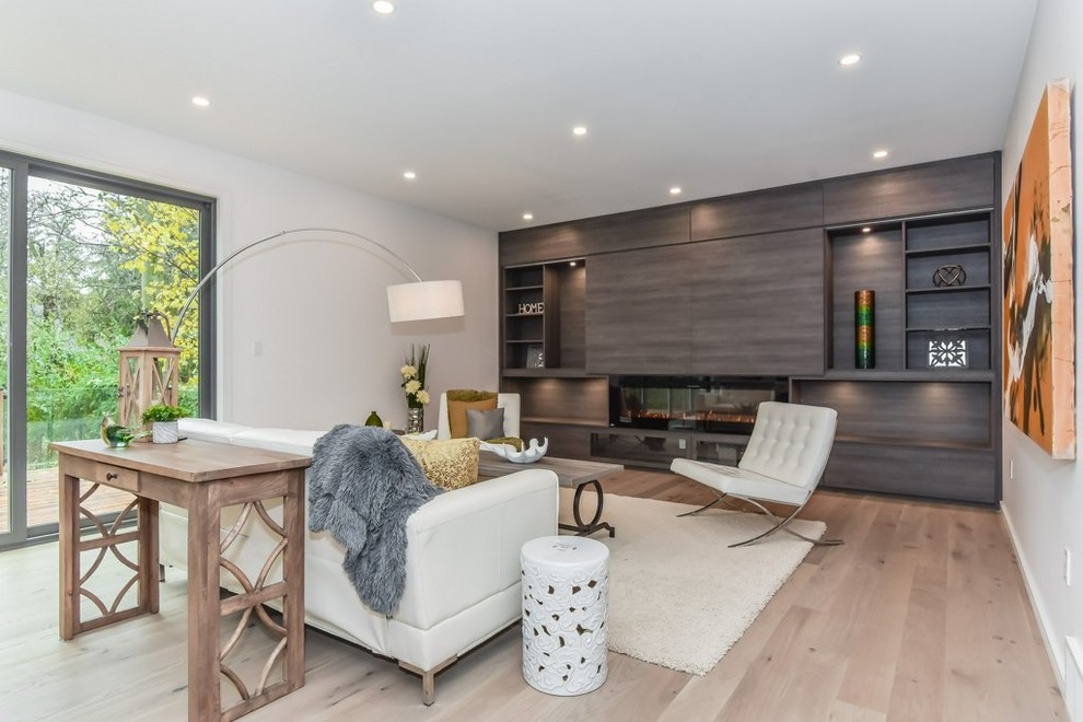 Large modern open concept living room in Toronto with white walls, light hardwood floors, a ribbon fireplace, a wood fireplace surround, no tv and beige floor.