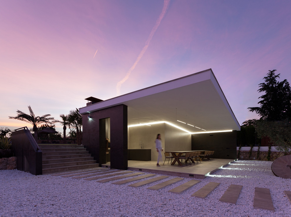 Modelo de terraza minimalista en anexo de casas con cocina exterior y suelo de baldosas