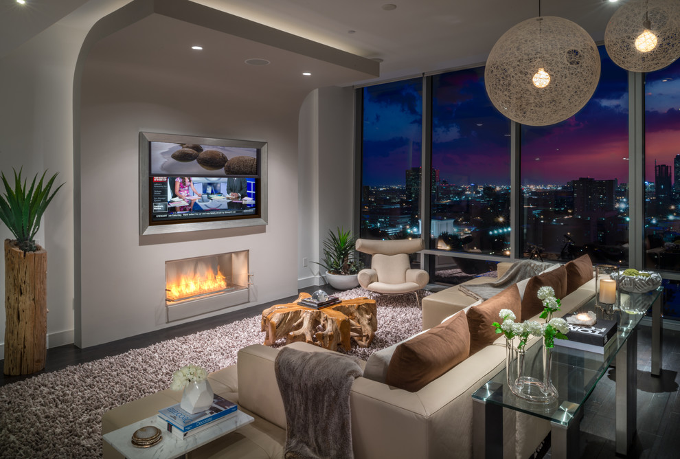 Photo of a large contemporary living room in Houston with white walls, dark hardwood floors, a ribbon fireplace and a concealed tv.