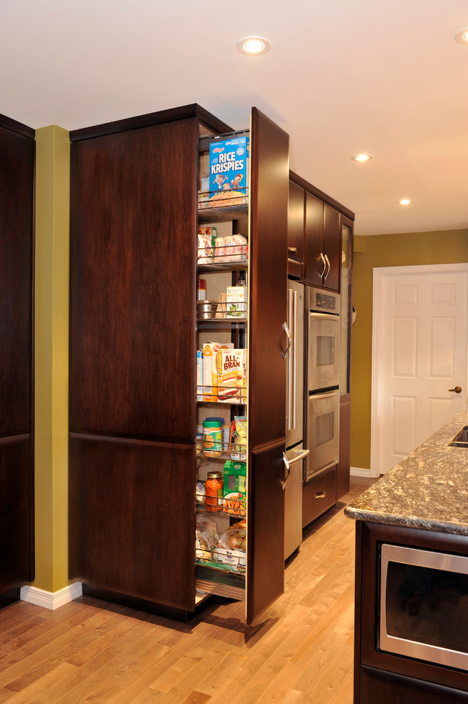 Transitional dark wood floor kitchen photo in Toronto with a double-bowl sink, flat-panel cabinets, dark wood cabinets, granite countertops, mirror backsplash, stainless steel appliances and an island