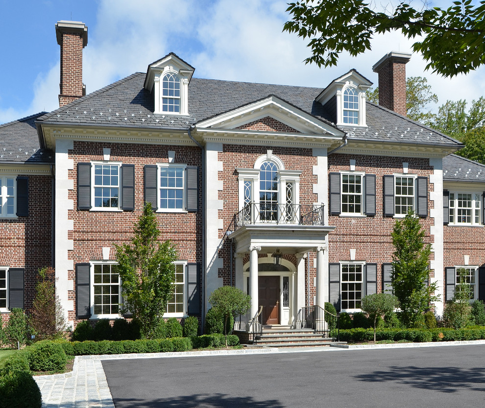Large elegant red three-story brick house exterior photo in Other with a hip roof and a shingle roof