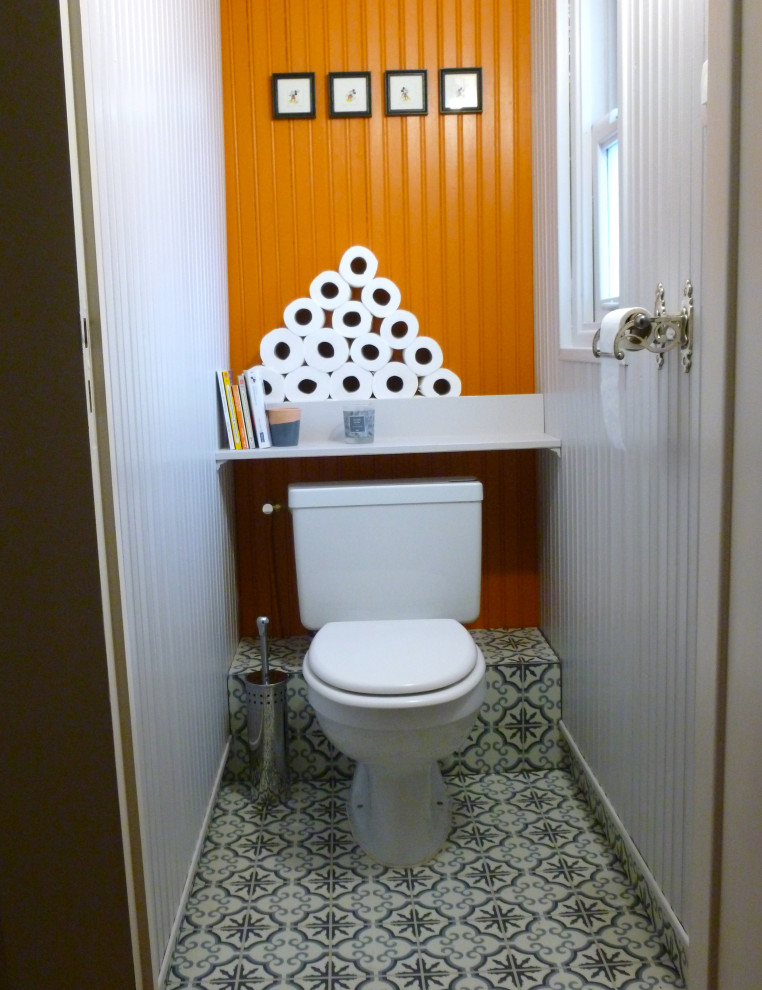 Inredning av ett modernt litet toalett, med en toalettstol med hel cisternkåpa och orange väggar