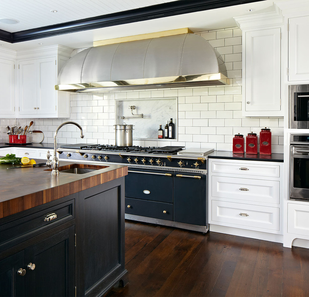 This is an example of a transitional kitchen in New York with shaker cabinets, white cabinets, white splashback, subway tile splashback, dark hardwood floors and black appliances.