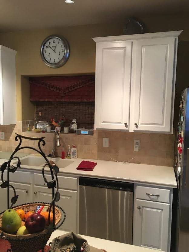 Example of a mid-sized transitional l-shaped enclosed kitchen design with an integrated sink, raised-panel cabinets, white cabinets, laminate countertops, beige backsplash, porcelain backsplash, stainless steel appliances, an island and white countertops
