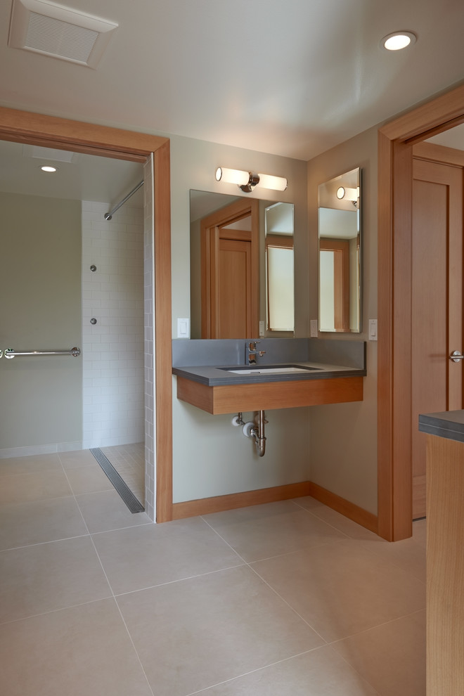 Inspiration for a mid-sized contemporary master bathroom in Seattle with flat-panel cabinets, medium wood cabinets, a curbless shower, white tile, subway tile, white walls, ceramic floors, an undermount sink, soapstone benchtops and a two-piece toilet.