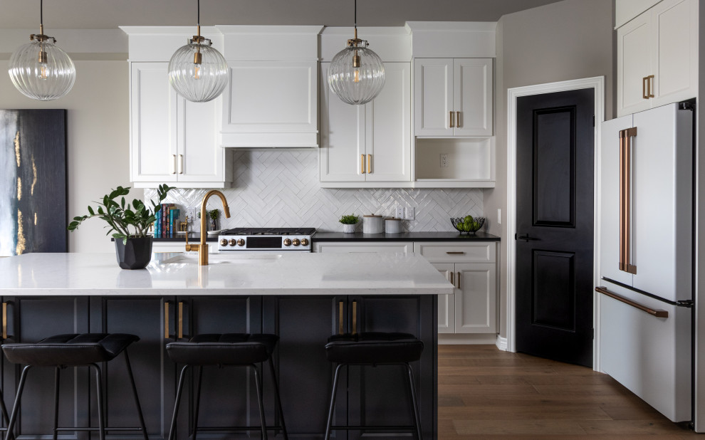 Photo of a large transitional single-wall eat-in kitchen in Toronto with an undermount sink, white cabinets, white splashback, white appliances, with island, shaker cabinets, quartz benchtops, ceramic splashback, light hardwood floors, white floor and black benchtop.