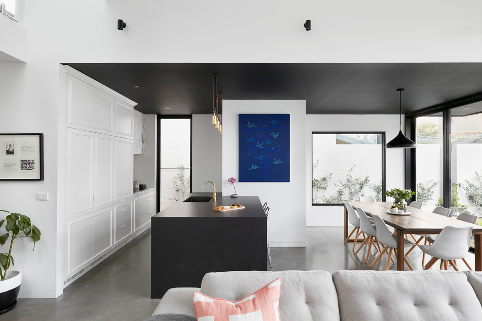 Design ideas for a mid-sized traditional l-shaped eat-in kitchen in Melbourne with an undermount sink, beaded inset cabinets, white cabinets, quartz benchtops, grey splashback, marble splashback, coloured appliances, concrete floors, with island, grey floor and black benchtop.