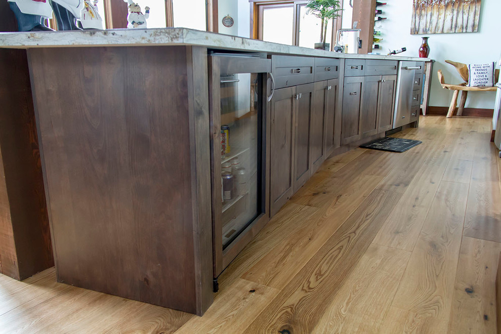 Example of a mid-sized mountain style galley light wood floor open concept kitchen design in Calgary with a drop-in sink, shaker cabinets, brown cabinets, laminate countertops, multicolored backsplash, stone tile backsplash, stainless steel appliances and an island