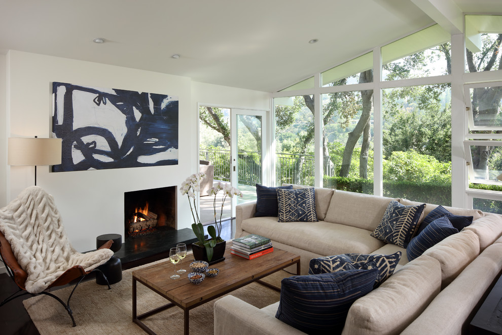 Country living room in San Francisco with a standard fireplace, black floor and white walls.
