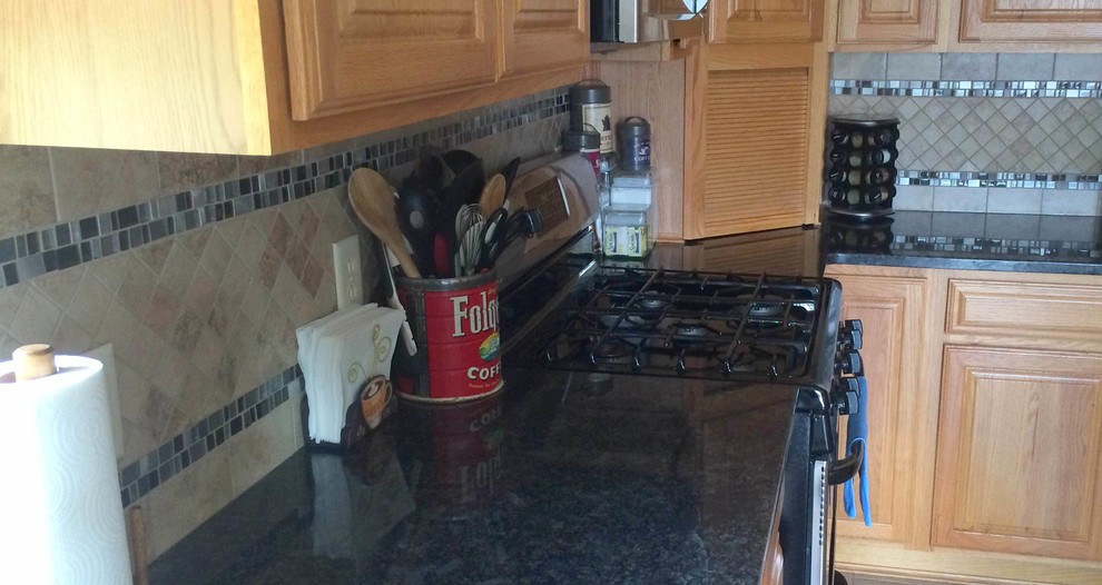 Inspiration for a mid-sized timeless u-shaped eat-in kitchen remodel with raised-panel cabinets, medium tone wood cabinets, granite countertops, multicolored backsplash, porcelain backsplash, stainless steel appliances and black countertops