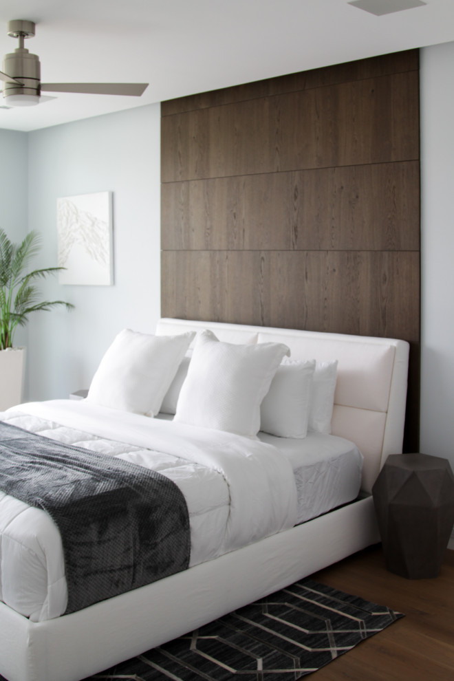 This is an example of a large contemporary guest bedroom in Miami with white walls, light hardwood floors and beige floor.