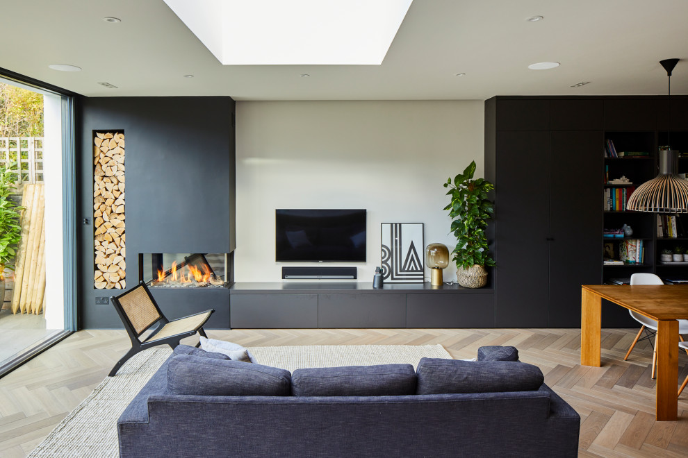 Inspiration for a contemporary open concept living room in Surrey with beige walls, light hardwood floors, beige floor, a corner fireplace, a plaster fireplace surround and a wall-mounted tv.