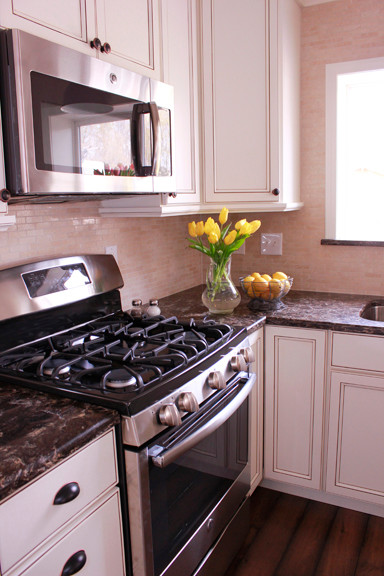 Small transitional u-shaped dark wood floor enclosed kitchen photo with an undermount sink, beaded inset cabinets, white cabinets, quartzite countertops, beige backsplash and stainless steel appliances