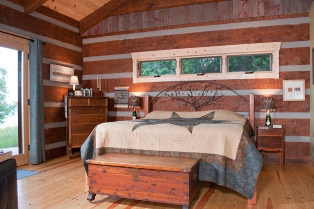 Example of a large mountain style master light wood floor bedroom design with brown walls