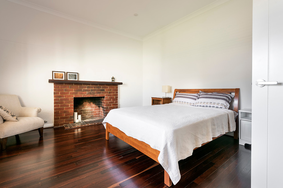 Design ideas for a large contemporary master bedroom in Perth with white walls, dark hardwood floors, a standard fireplace and a brick fireplace surround.