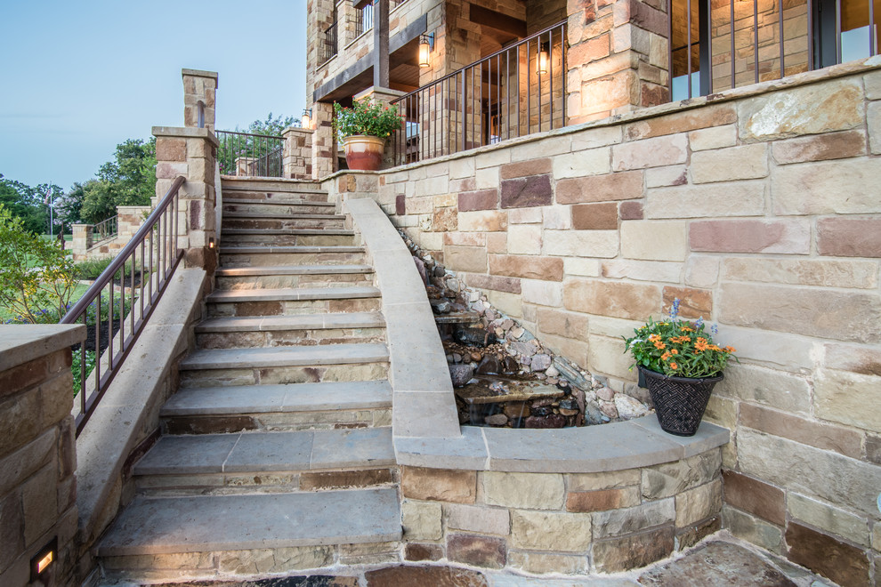 Large mediterranean front yard verandah in Austin with a water feature, natural stone pavers and a roof extension.