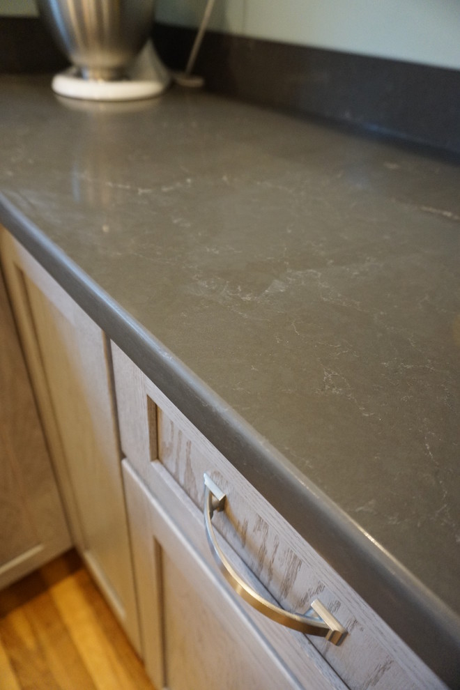 Mid-sized transitional u-shaped medium tone wood floor eat-in kitchen photo in Boston with an undermount sink, shaker cabinets, gray cabinets, quartz countertops, black backsplash, stainless steel appliances and an island