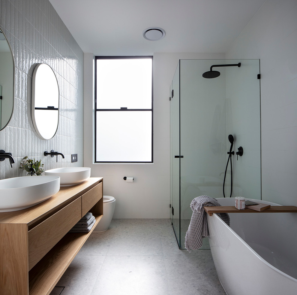 Design ideas for a mid-sized beach style bathroom in Sydney with open cabinets, brown cabinets, a freestanding tub, an alcove shower, white tile, ceramic tile, white walls, concrete floors, a vessel sink, wood benchtops, grey floor, a hinged shower door and brown benchtops.