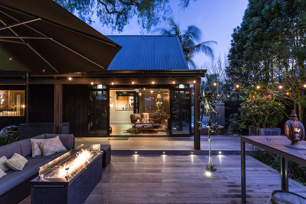 This is an example of a mid-sized industrial courtyard patio in Auckland with a fire feature, decking and no cover.